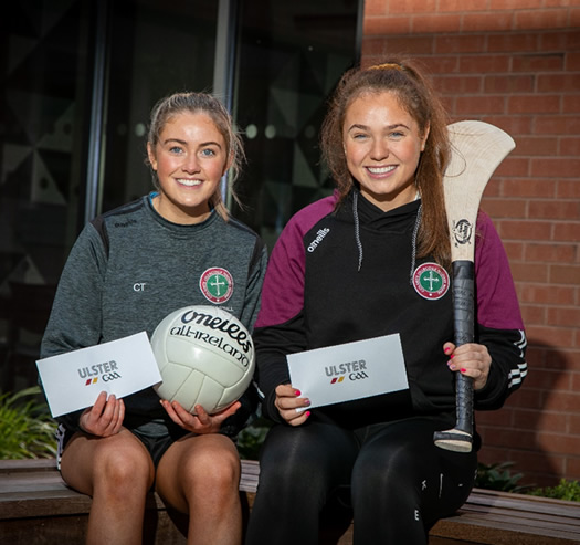 Two St Mary's students, Claire Teague and Shanna Cassidy, holding their Ulster GAA student bursaries.  Claire also holding a gaelic football and Shanna holding a camogie stick.