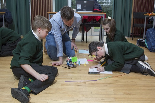 A student teacher helping children program a robot