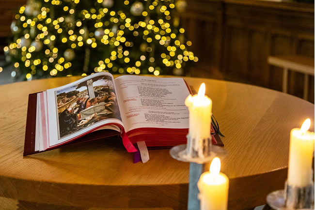 Christmas tree lights in the background with bible open on a table and candles in the foreground